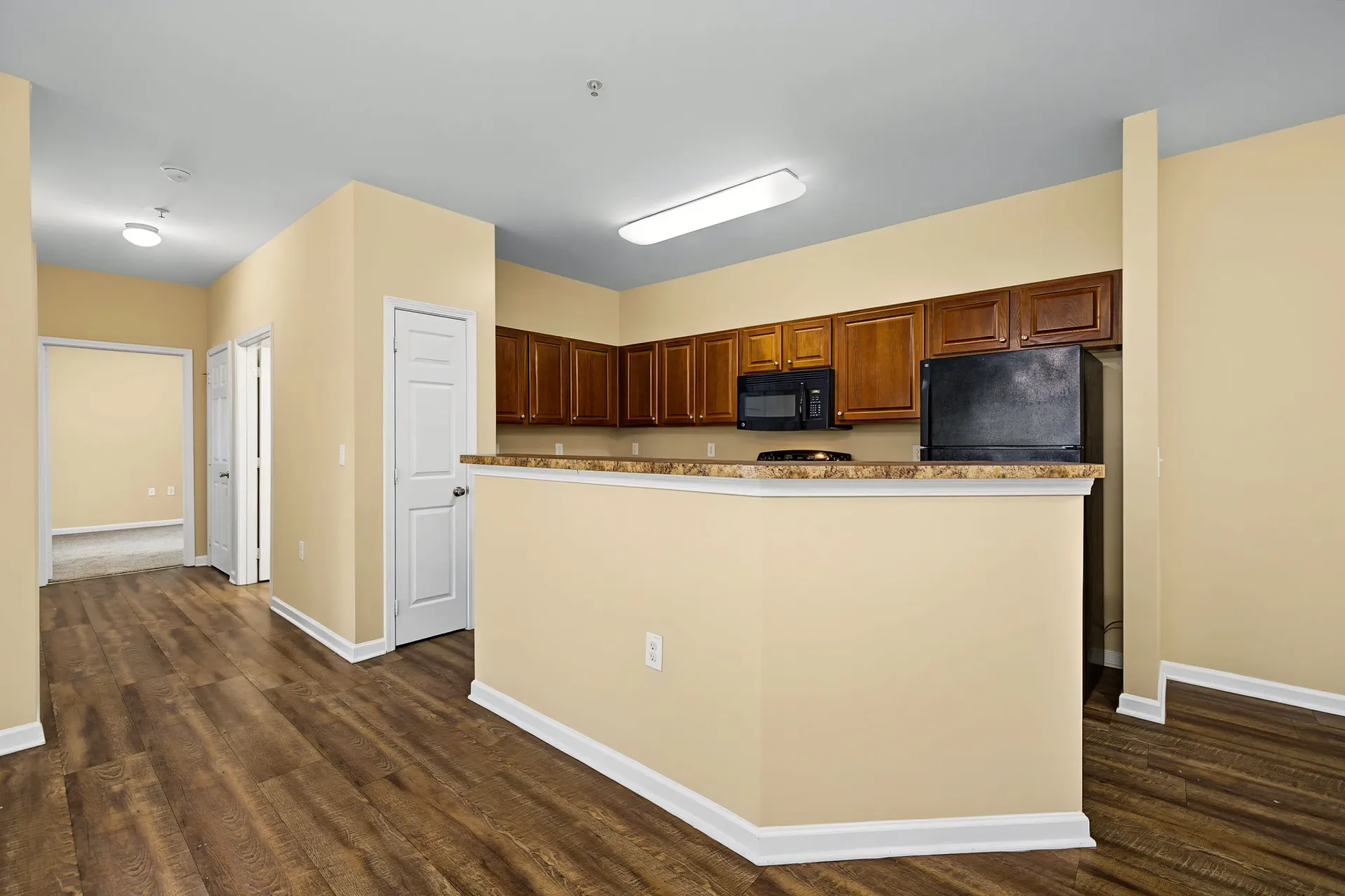 Open concept kitchen with dark wood cabinets and a peninsula.