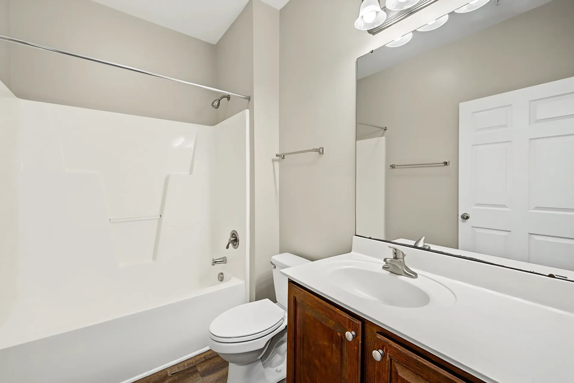 Bathroom with a bathtub, toilet, and vanity with sink and mirror.