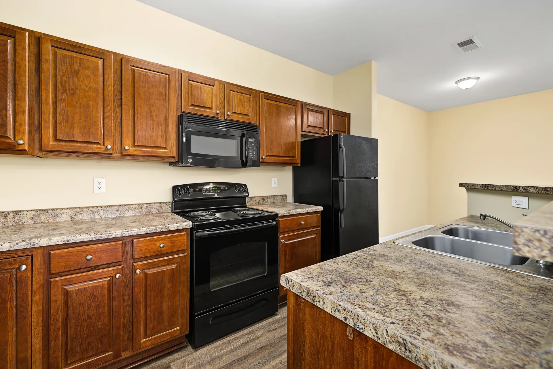 Kitchen with wood cabinets, black appliances, and granite countertops.