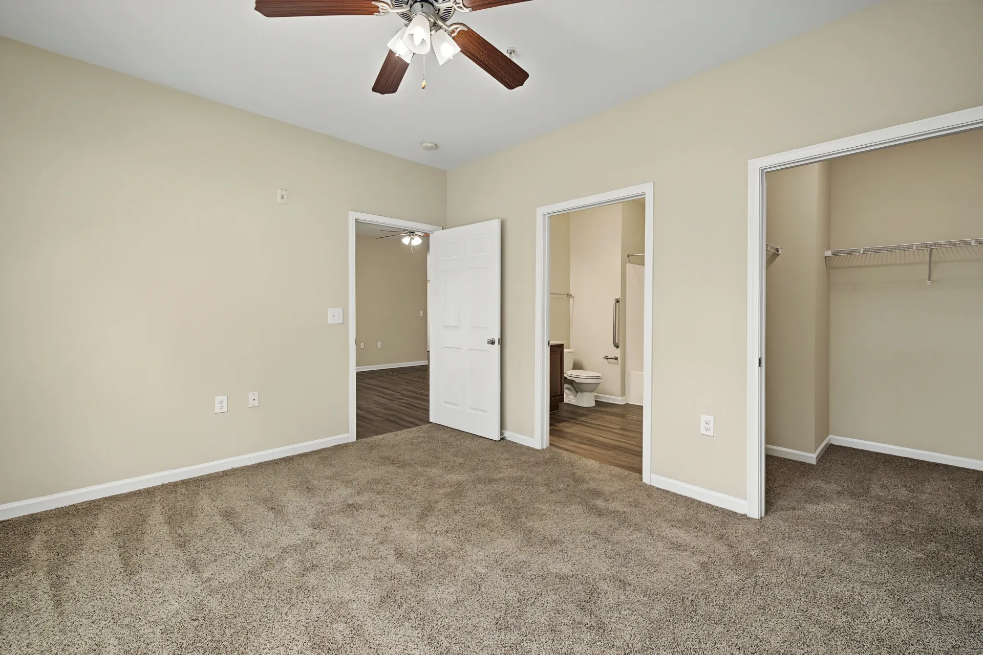 Bedroom with plush carpet, ceiling fan, and views into a bathroom and another room.