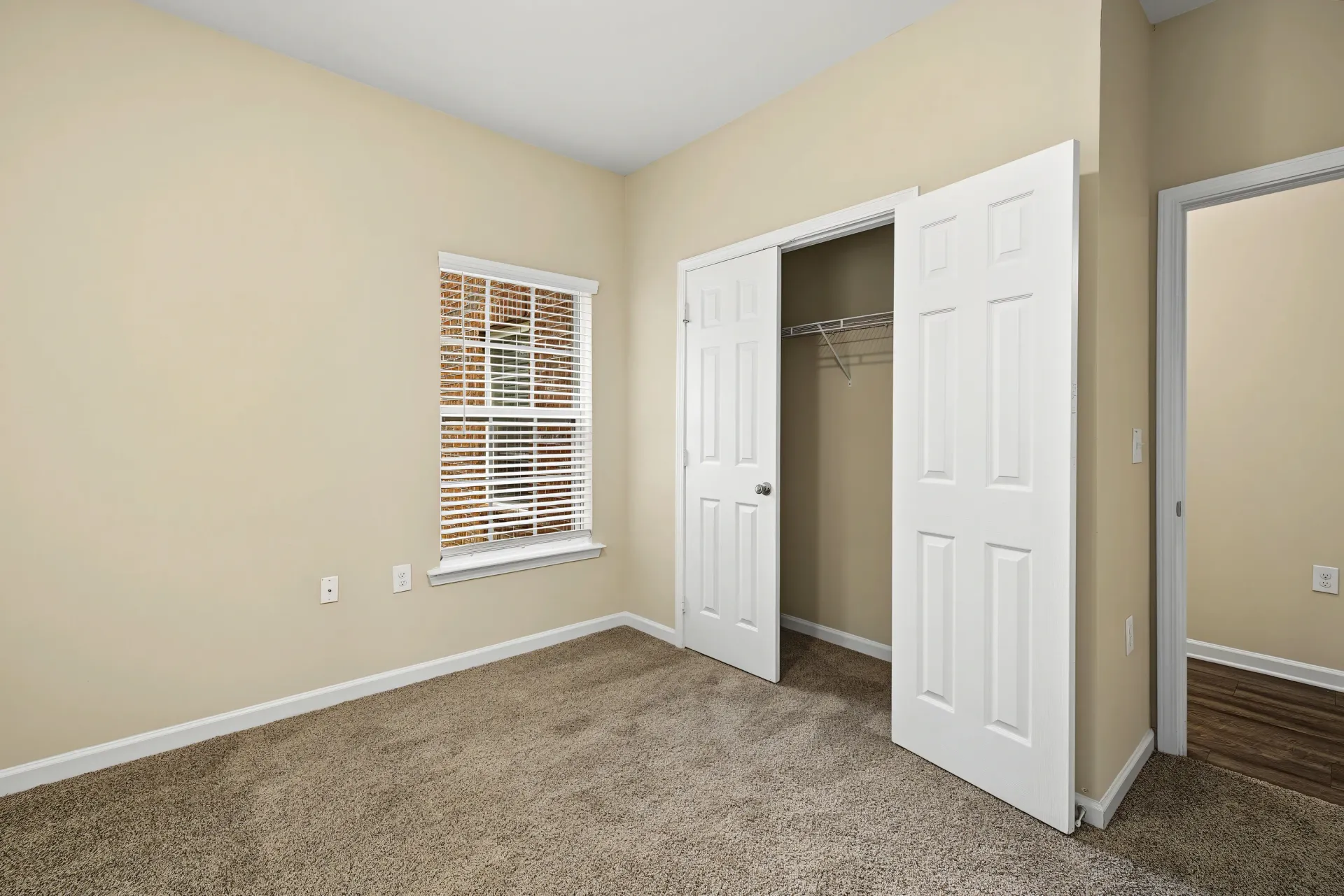 Bedroom closet with white bifold doors and a wire shelf.