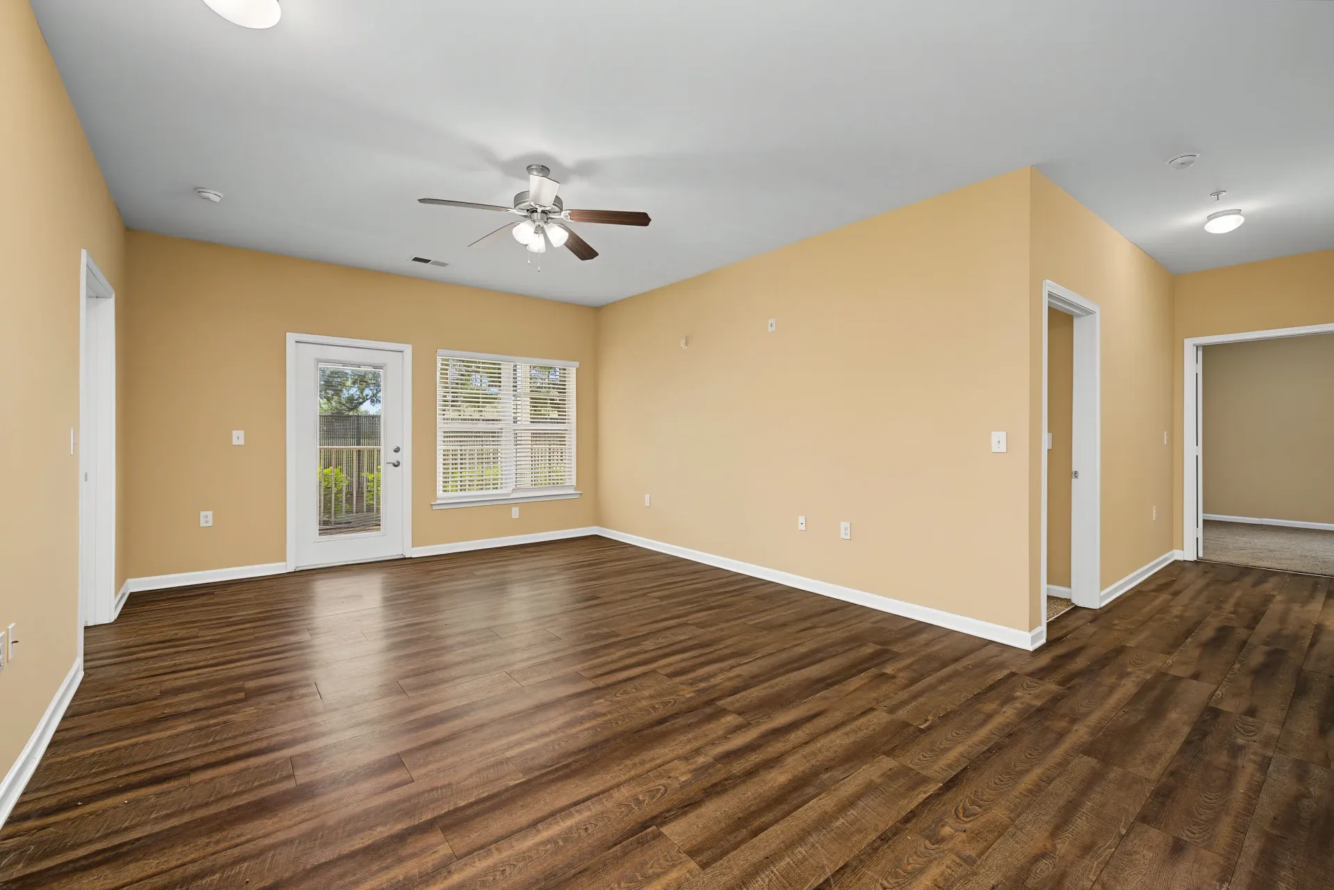 Interior view of an empty living room with wood floors and beige walls.