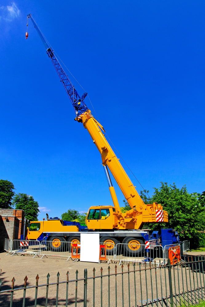 A Large Yellow Crane Is Sitting On Top Of A Construction Site — Smithys Crane Hire in Trinity Beach, QLD