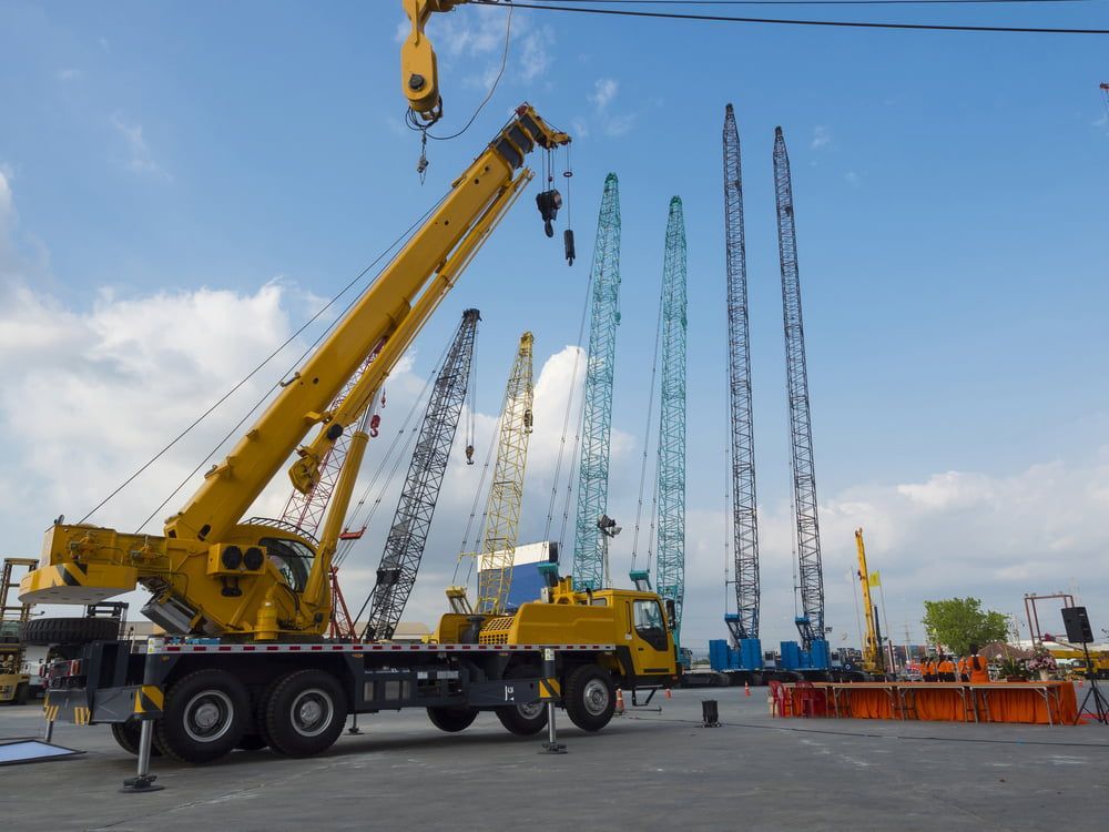 A Large Yellow Crane is Sitting on Top of a Truck at a Construction Site — Smithys Crane Hire in Port Douglas, QLD