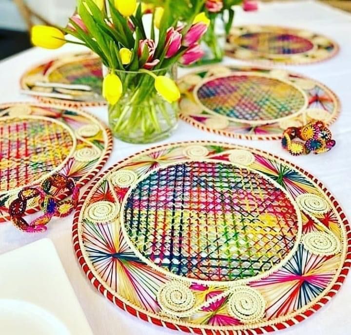 Manteles individuales tejidos de colores sobre un mantel blanco con jarrones de tulipanes, creando una atmósfera festiva en la mesa.