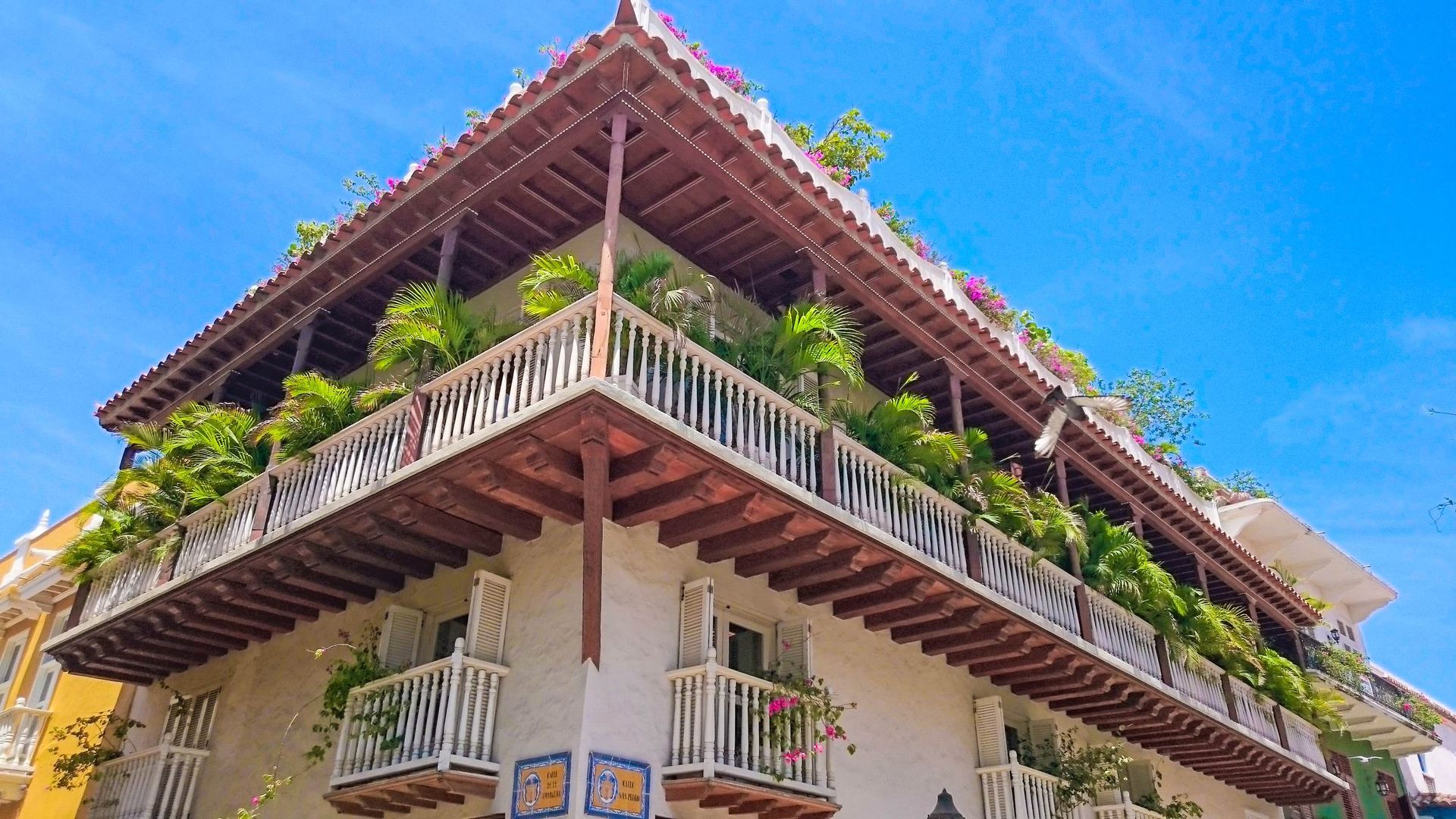 Un gran edificio blanco con un balcón y un cielo azul al fondo.
