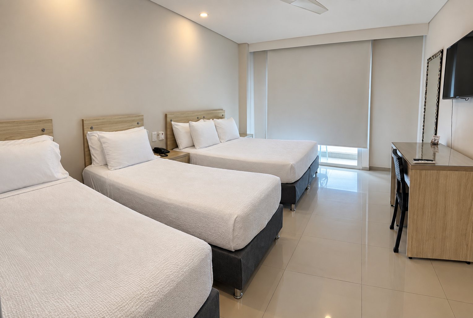 Una habitación de hotel con dos camas, un escritorio y un ventilador de techo.