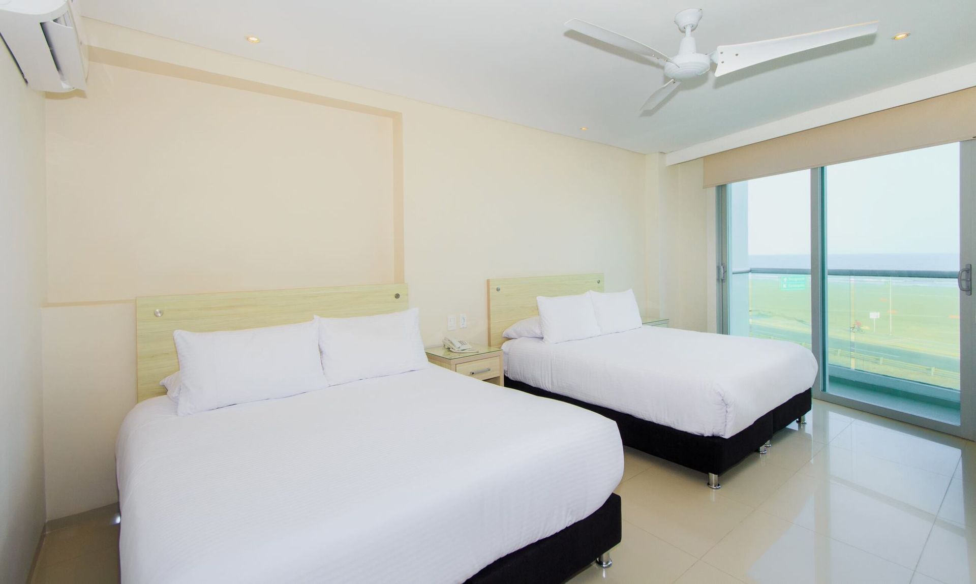 Una habitación de hotel con dos camas y ventilador de techo.