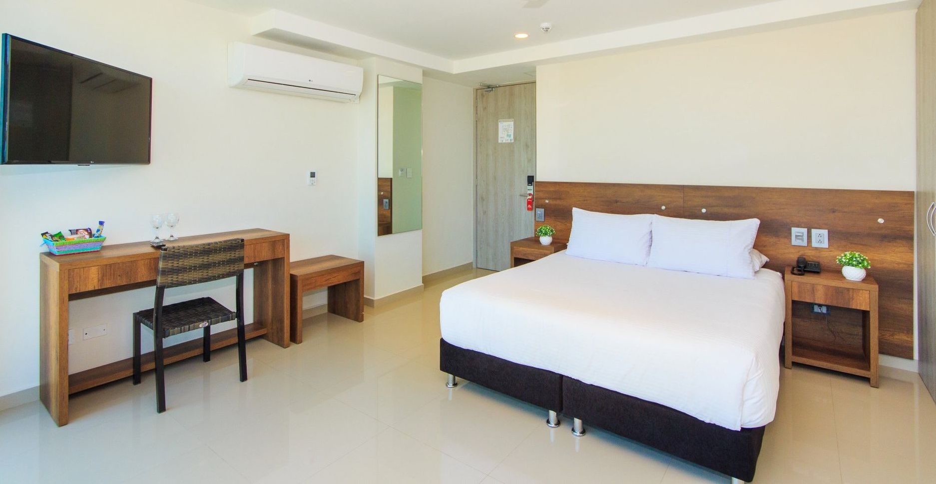 Una habitación de hotel con cama king size, escritorio y televisión.