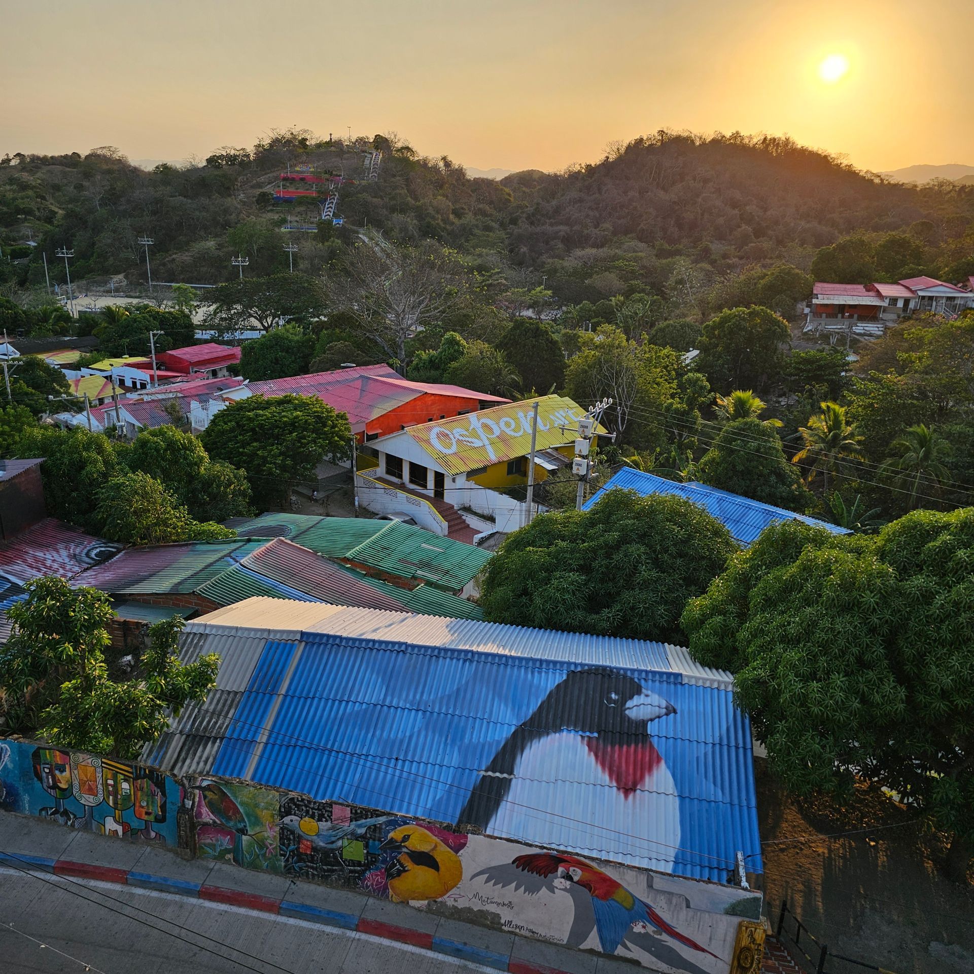 Casas coloridas enclavadas en un paisaje montañoso, con una puesta de sol de fondo.