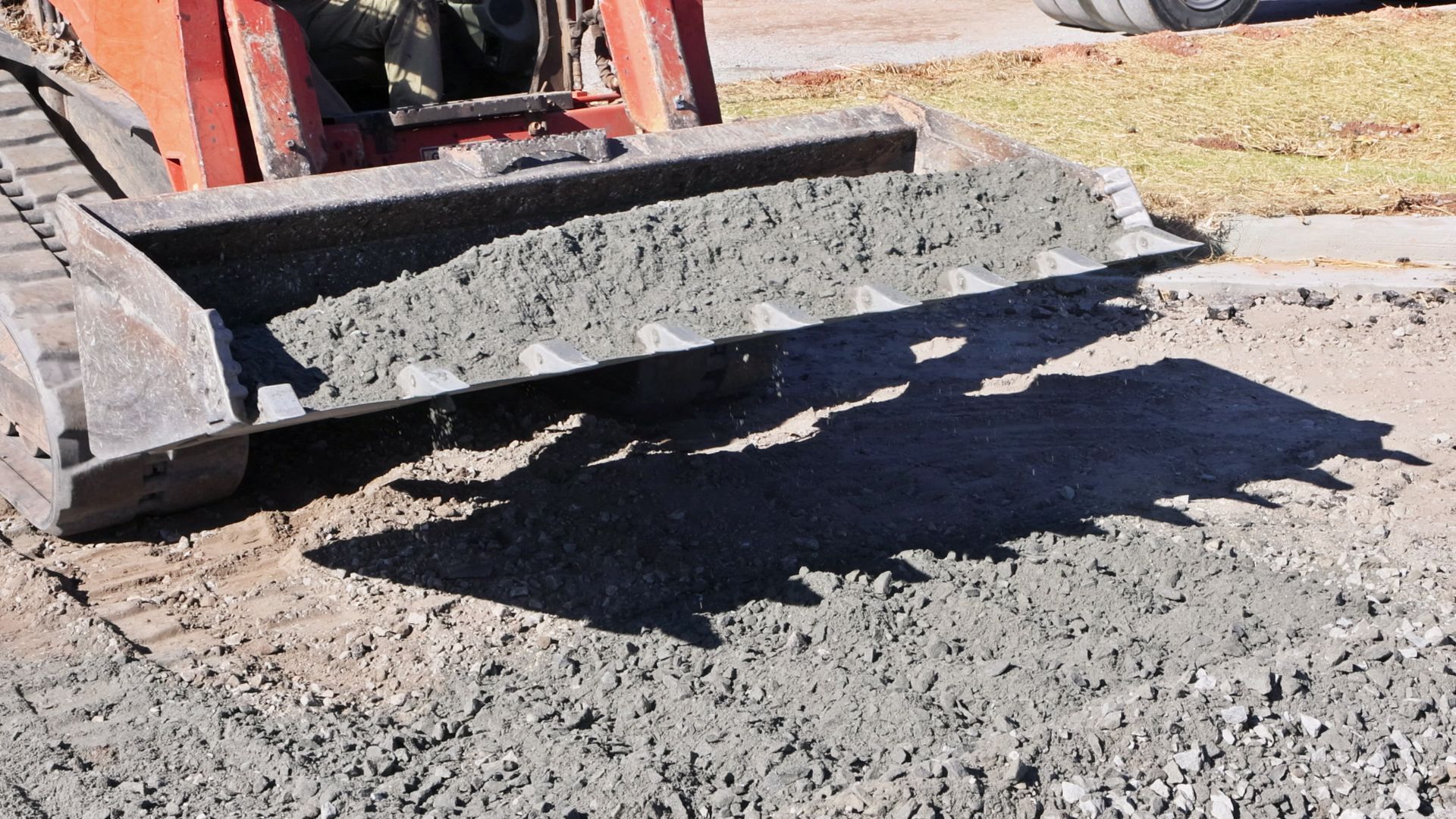 Construction vehicle dumping wet concrete onto a dirt surface Construction vehicle dumping wet concrete onto a dirt surface