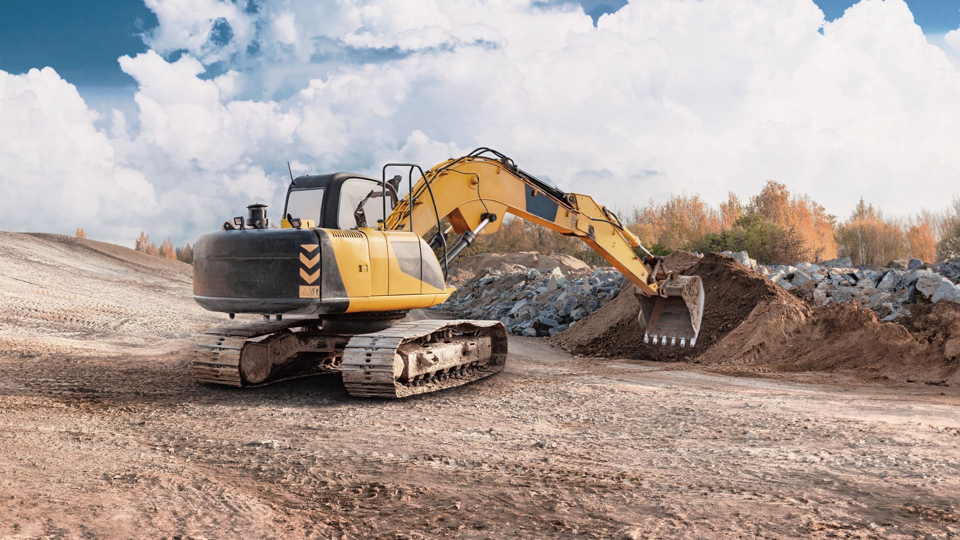 Yellow excavator digging dirt at a construction site under a cloudy sky Yellow excavator digging dirt at a construction site under a cloudy sky
