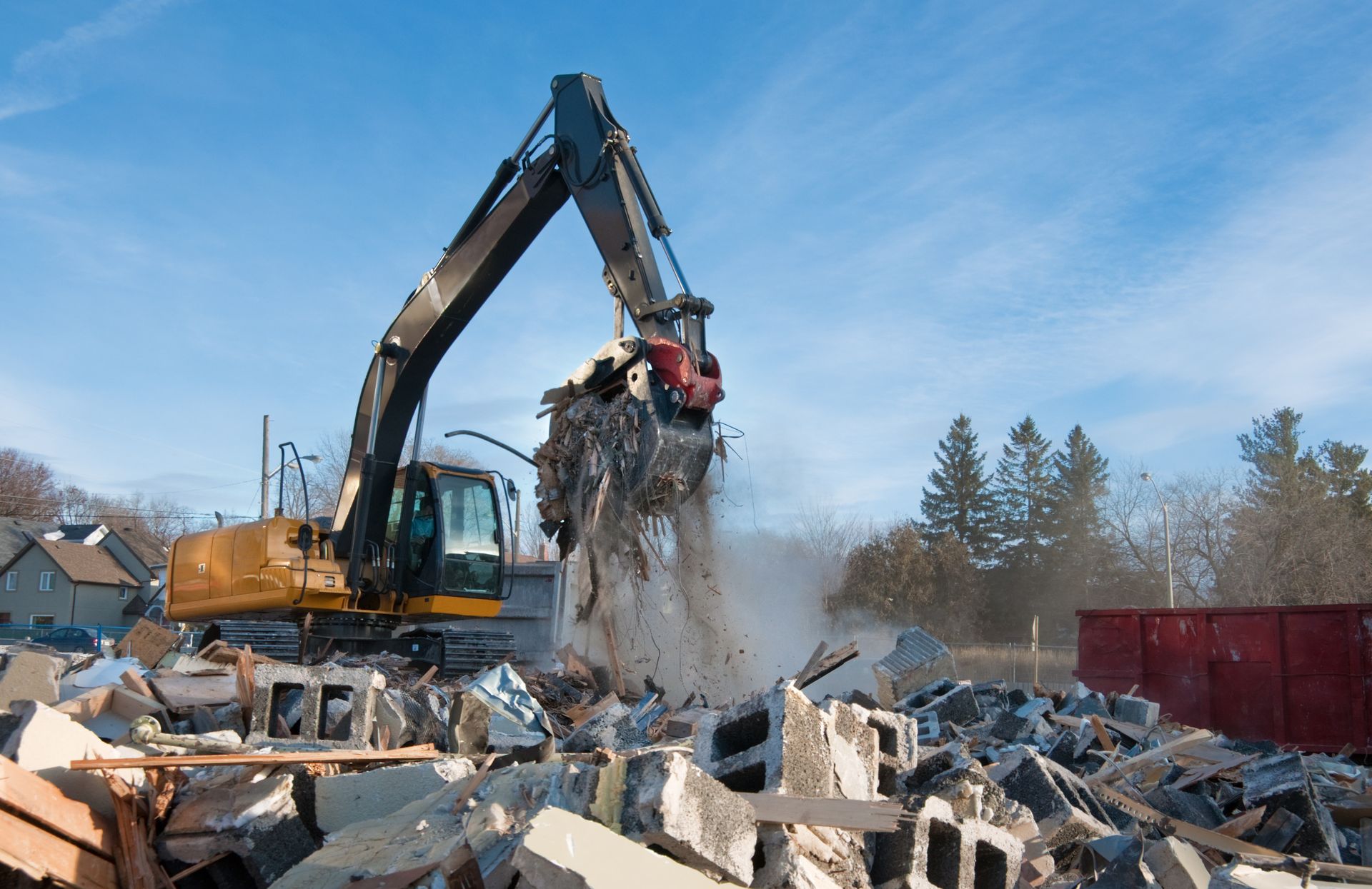 Excavator dumping rubble at a demolition site, with debris piles and a blue sky behind it Excavator dumping rubble at a demolition site, with debris piles and a blue sky behind it