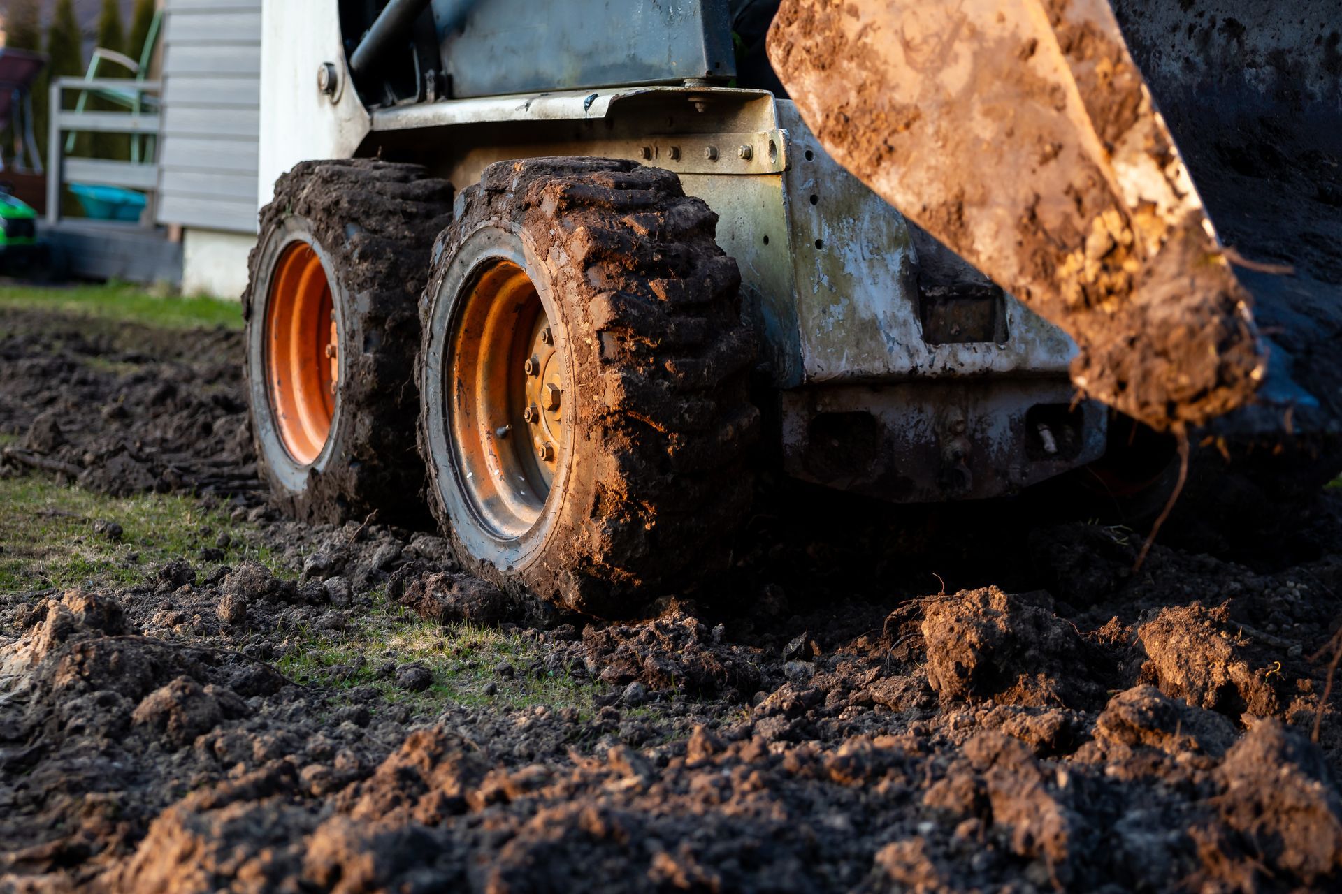 Mud-covered skid steer loader working on a muddy construction site Mud-covered skid steer loader working on a muddy construction site