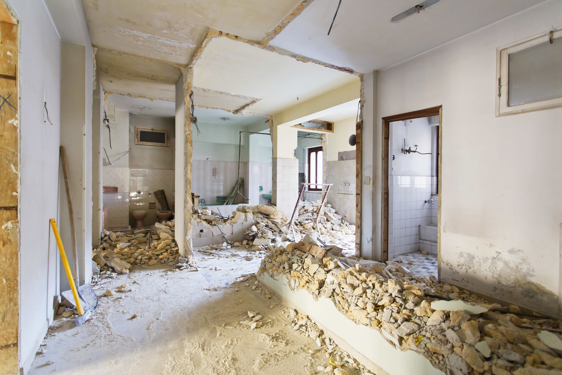 Demolition debris fills a damaged interior room with exposed walls and broken plaster. Demolition debris fills a damaged interior room with exposed walls and broken plaster.