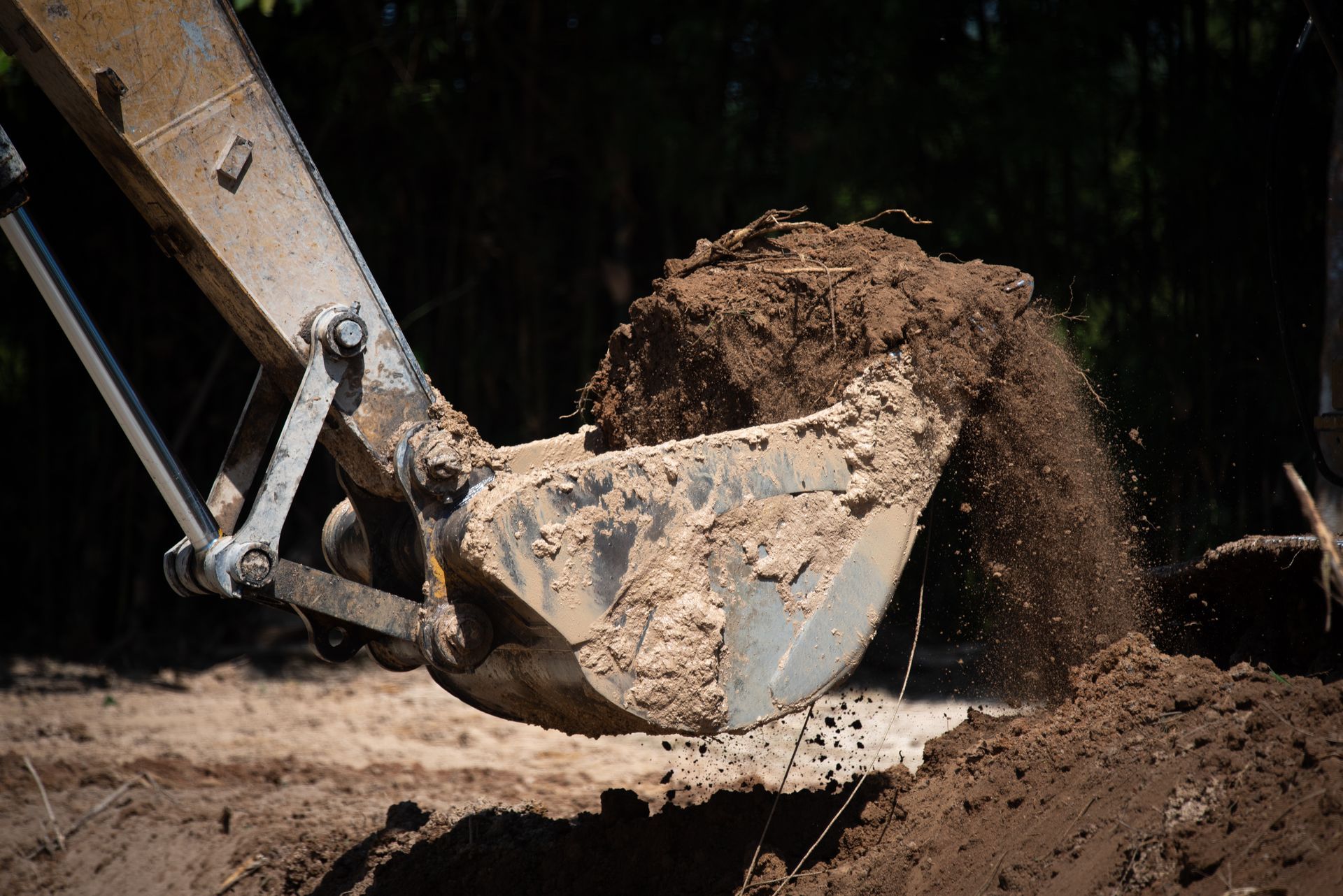 Excavator bucket dumping dirt at a construction site