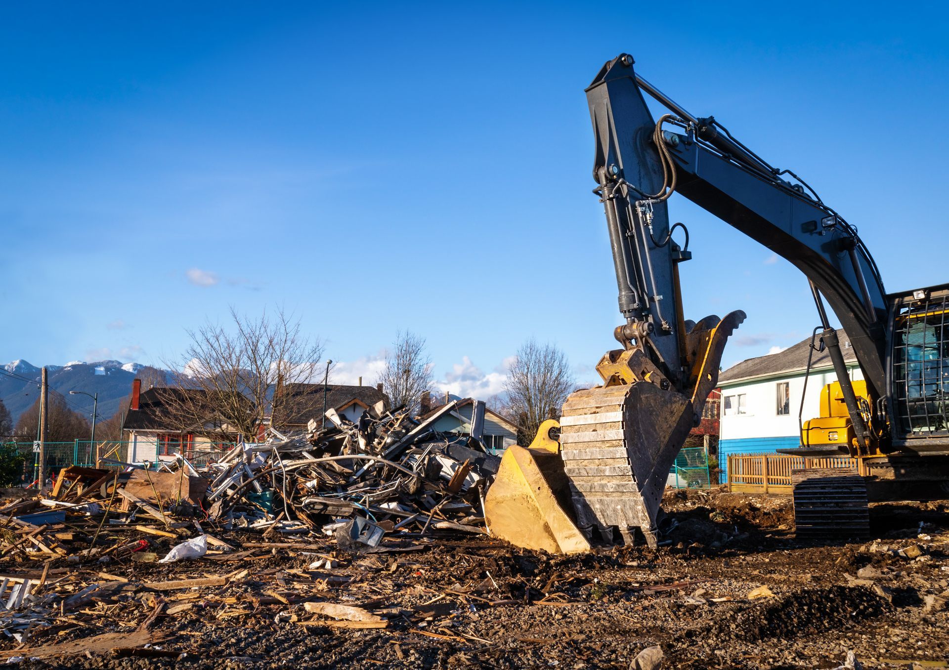 Excavator clearing rubble at a demolition site under a clear blue sky Excavator clearing rubble at a demolition site under a clear blue sky