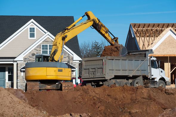 Excavator loading dirt into a dump truck at a residential construction site. Excavator loading dirt into a dump truck at a residential construction site.