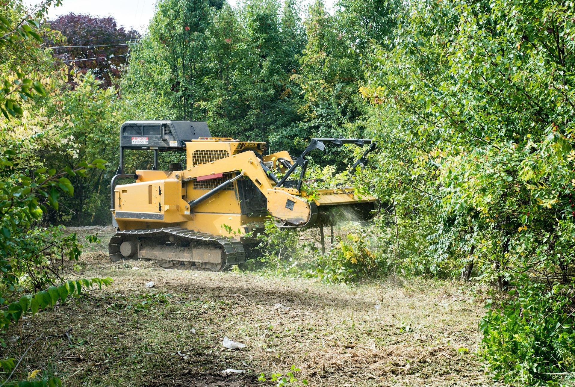 Yellow bulldozer clearing brush in a green wooded area Yellow bulldozer clearing brush in a green wooded area