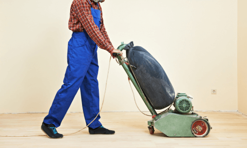 Worker floor sanding with floor sander