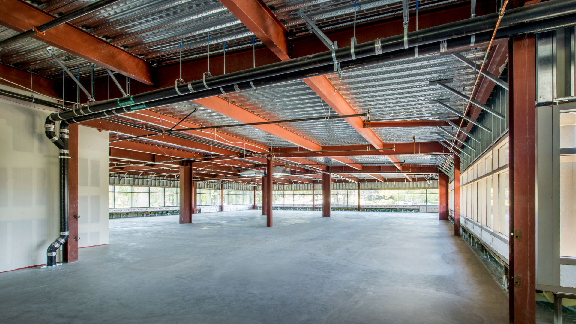 A large empty building with a lot of pipes hanging from the ceiling.