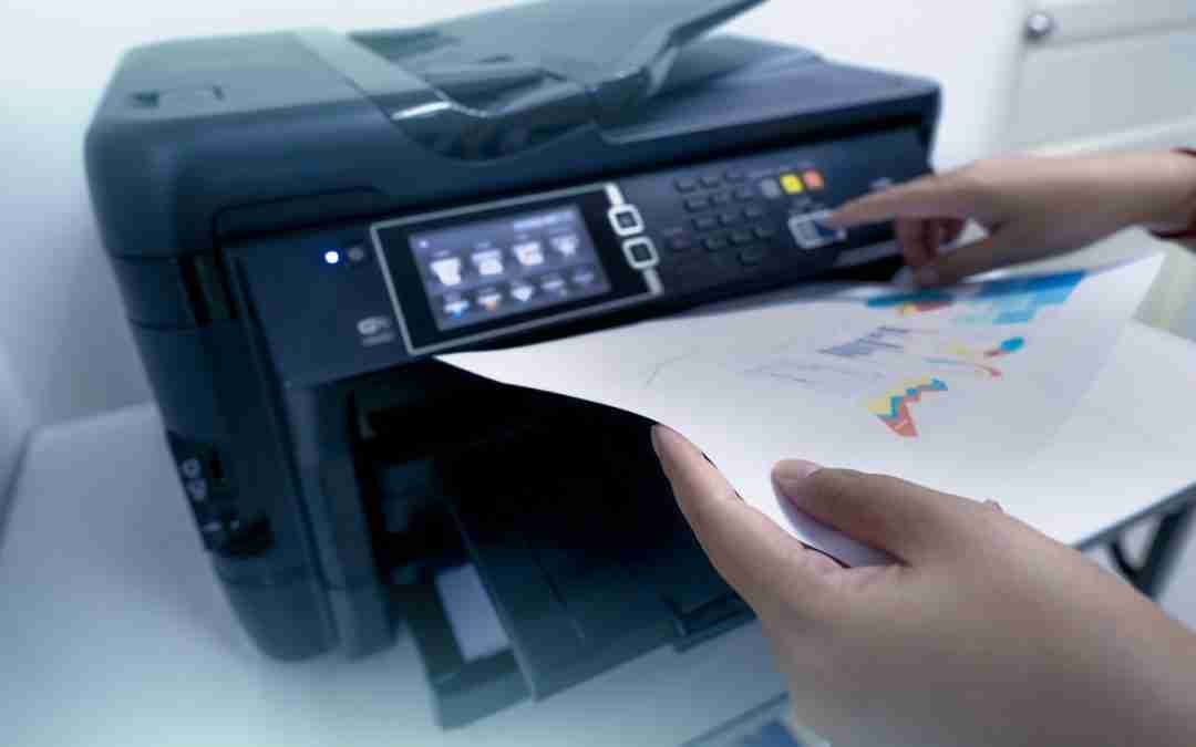 Hands feeding paper into a black multifunction printer with touchscreen display