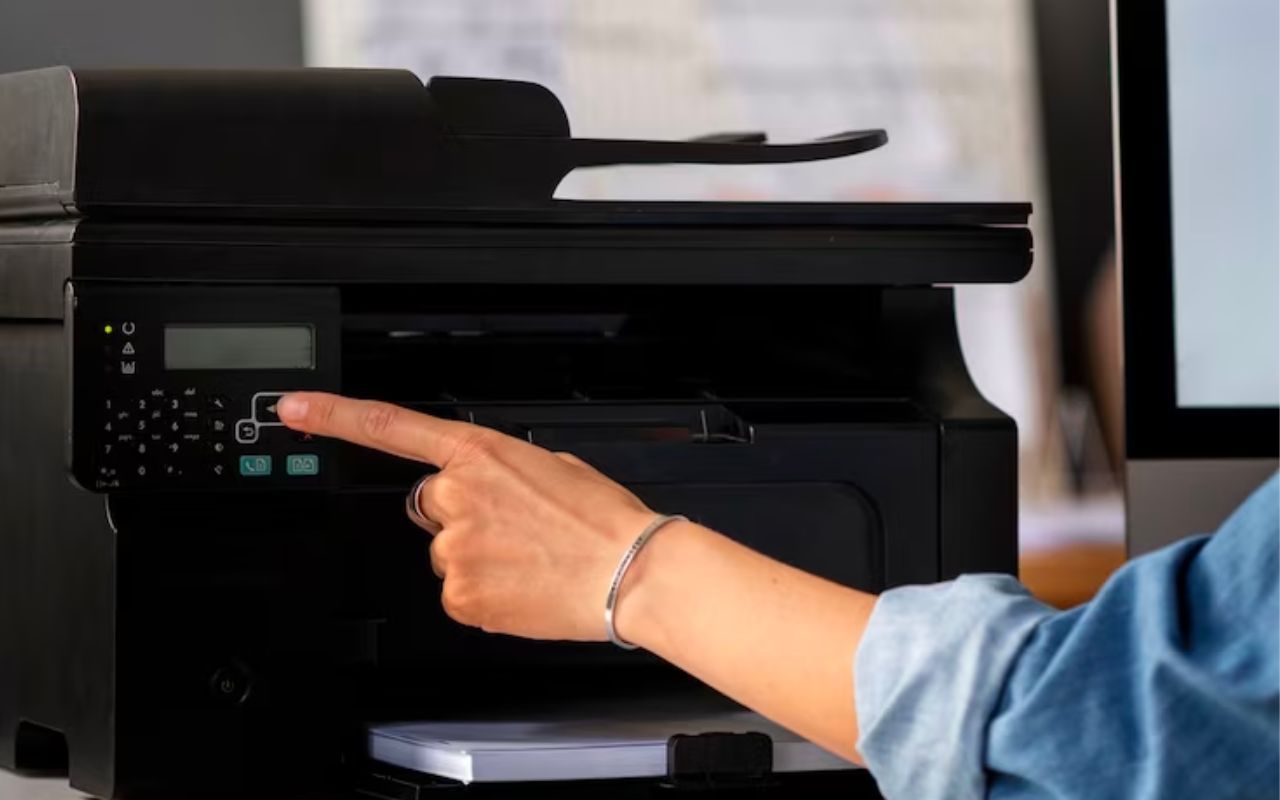 Hand pressing buttons on a black office printer/copier