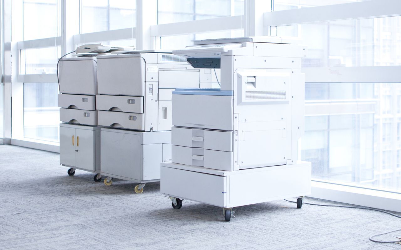 Two office copy machines on wheels in a bright modern room