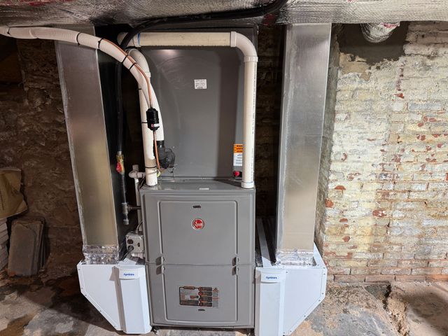 Gray furnace with ductwork installed in a brick basement.