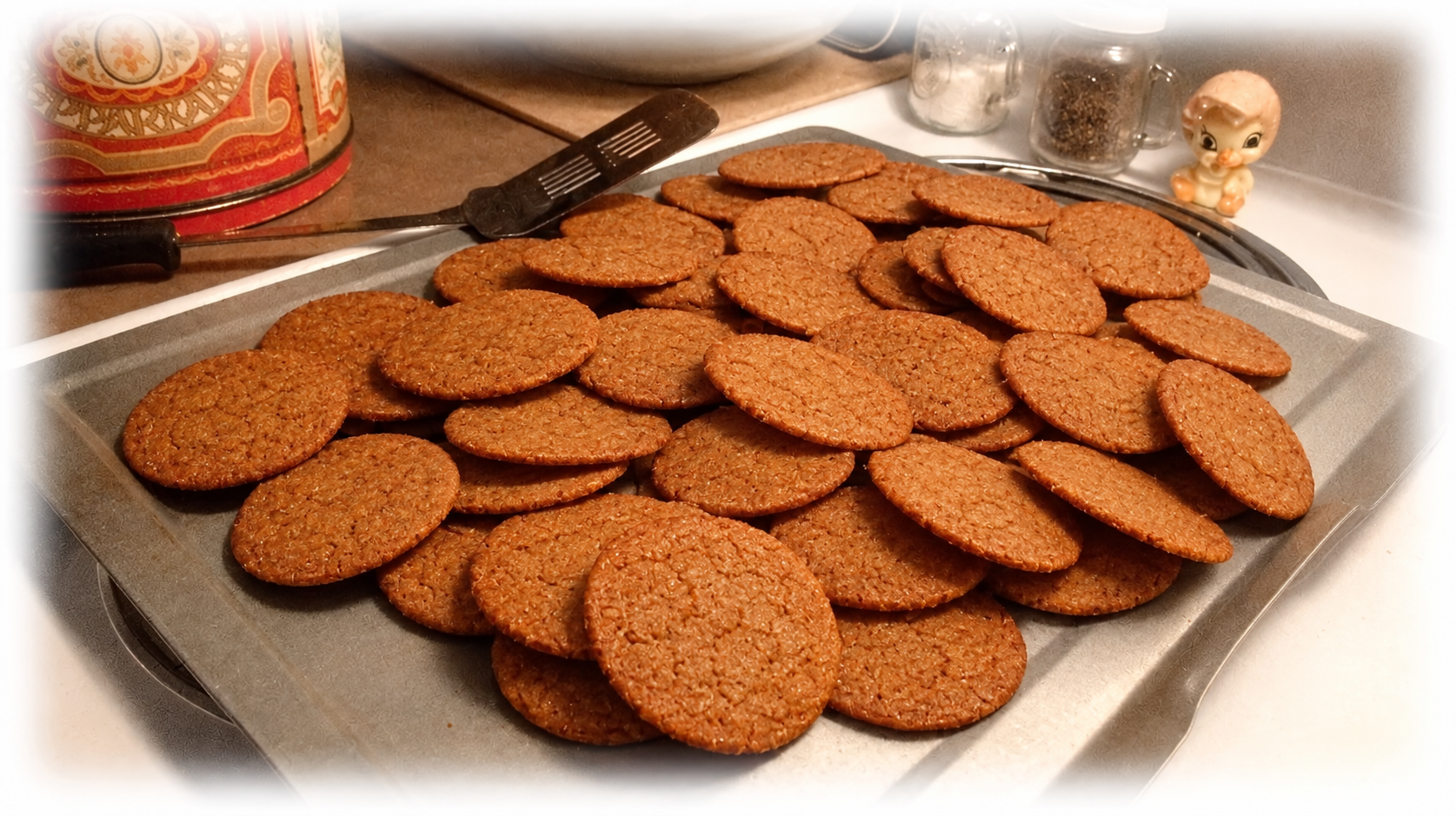 Plate of homemade chocolate cookies on a tray, with a cracked, baked finish and kitchen utensils nearby