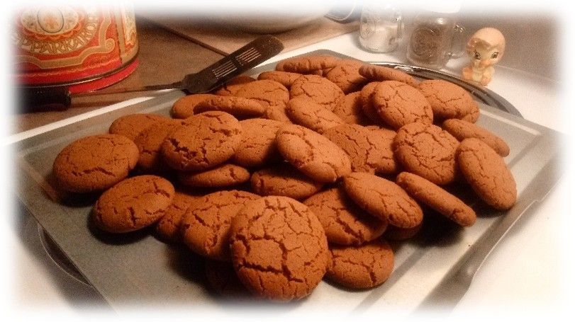 Plate of homemade chocolate cookies on a tray, with a cracked, baked finish and kitchen utensils nearby