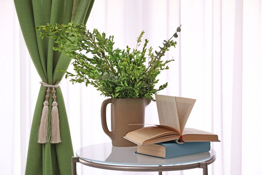 A Table with a Vase of Flowers and a Book on It — Junction Hill Nursery in Junction Hill, NSW