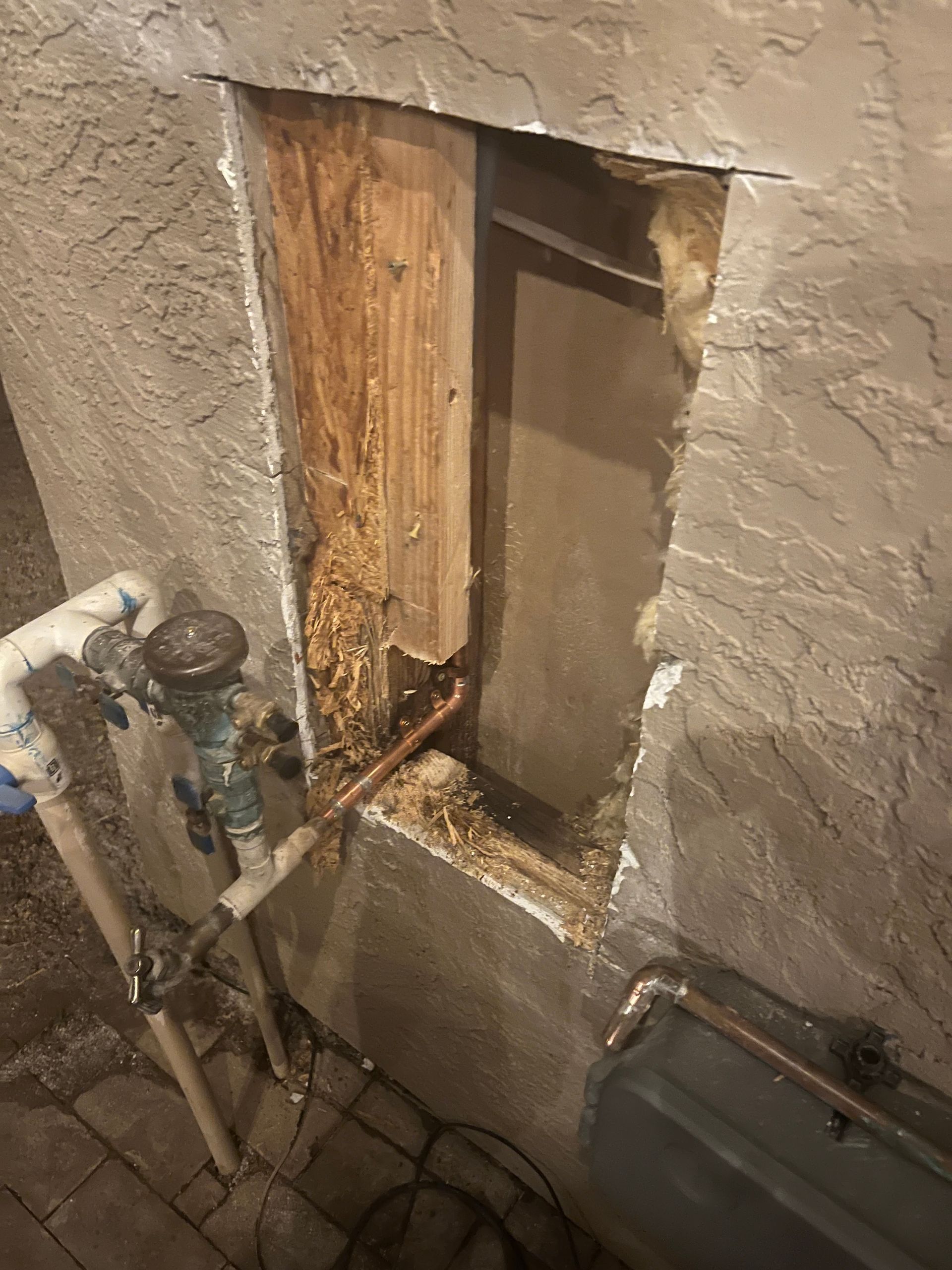 A hole in a wall with pipes coming out of it.