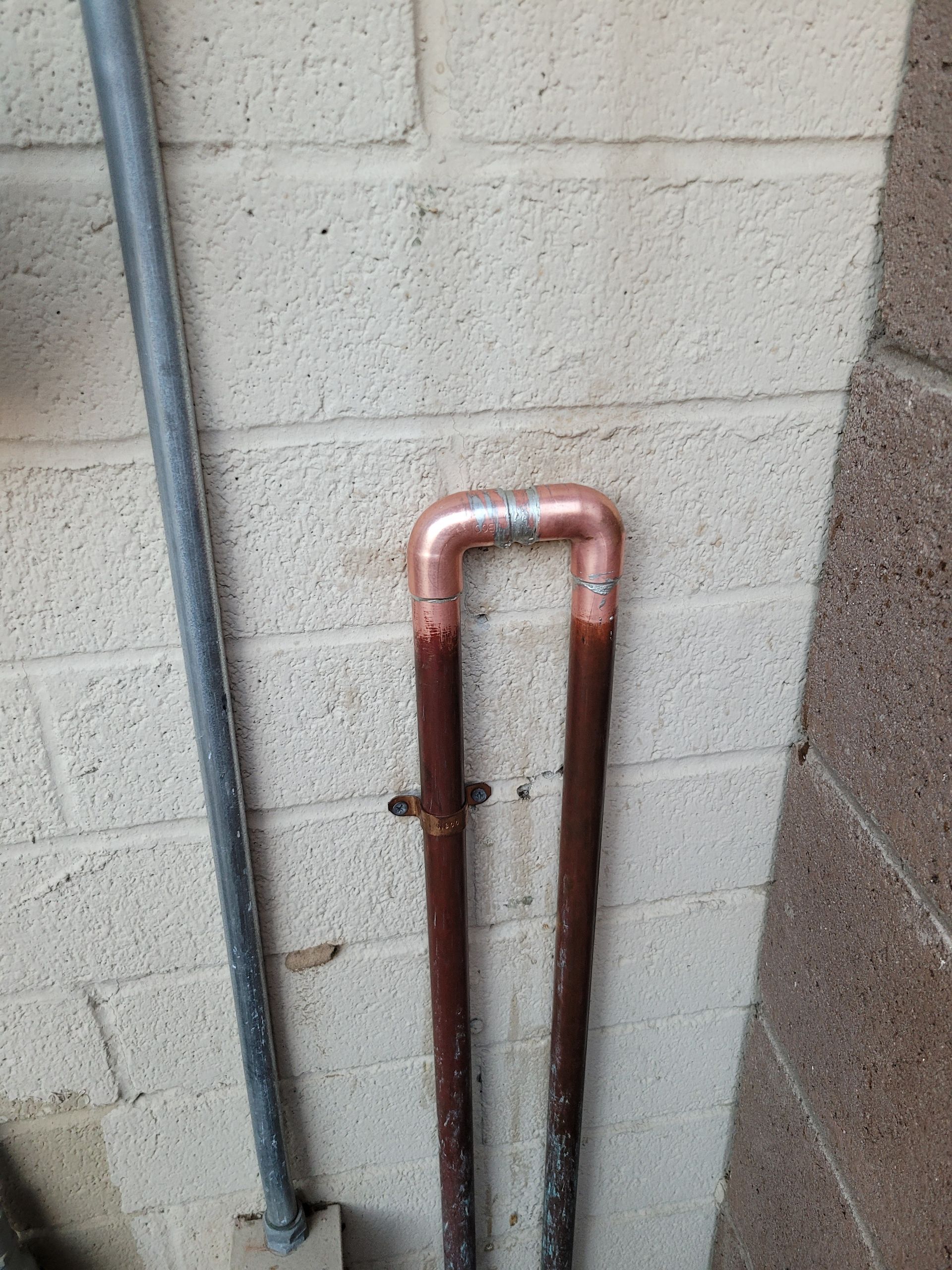 A close up of a copper pipe on a brick wall.