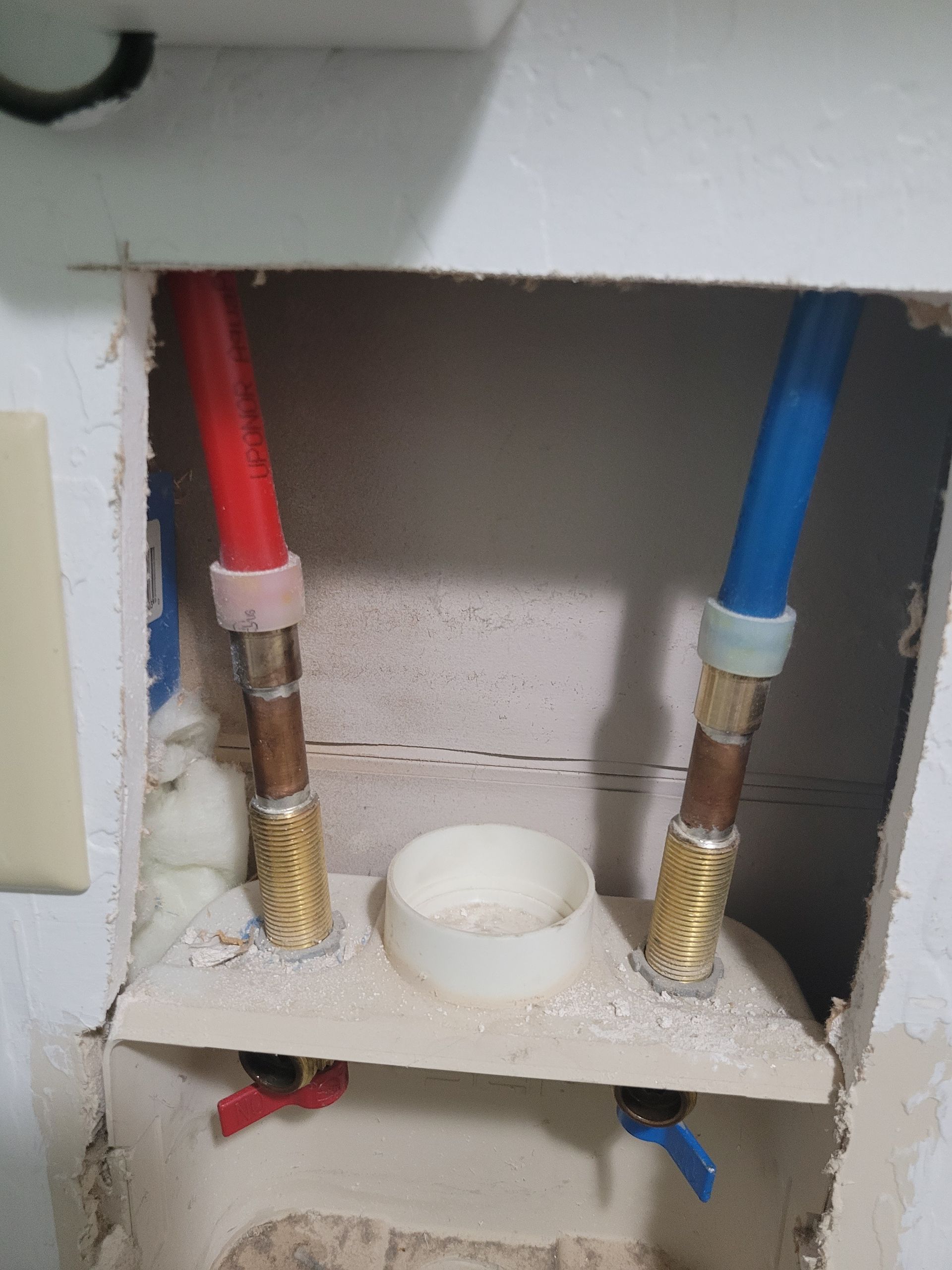 A bathroom sink with red and blue pipes coming out of it.