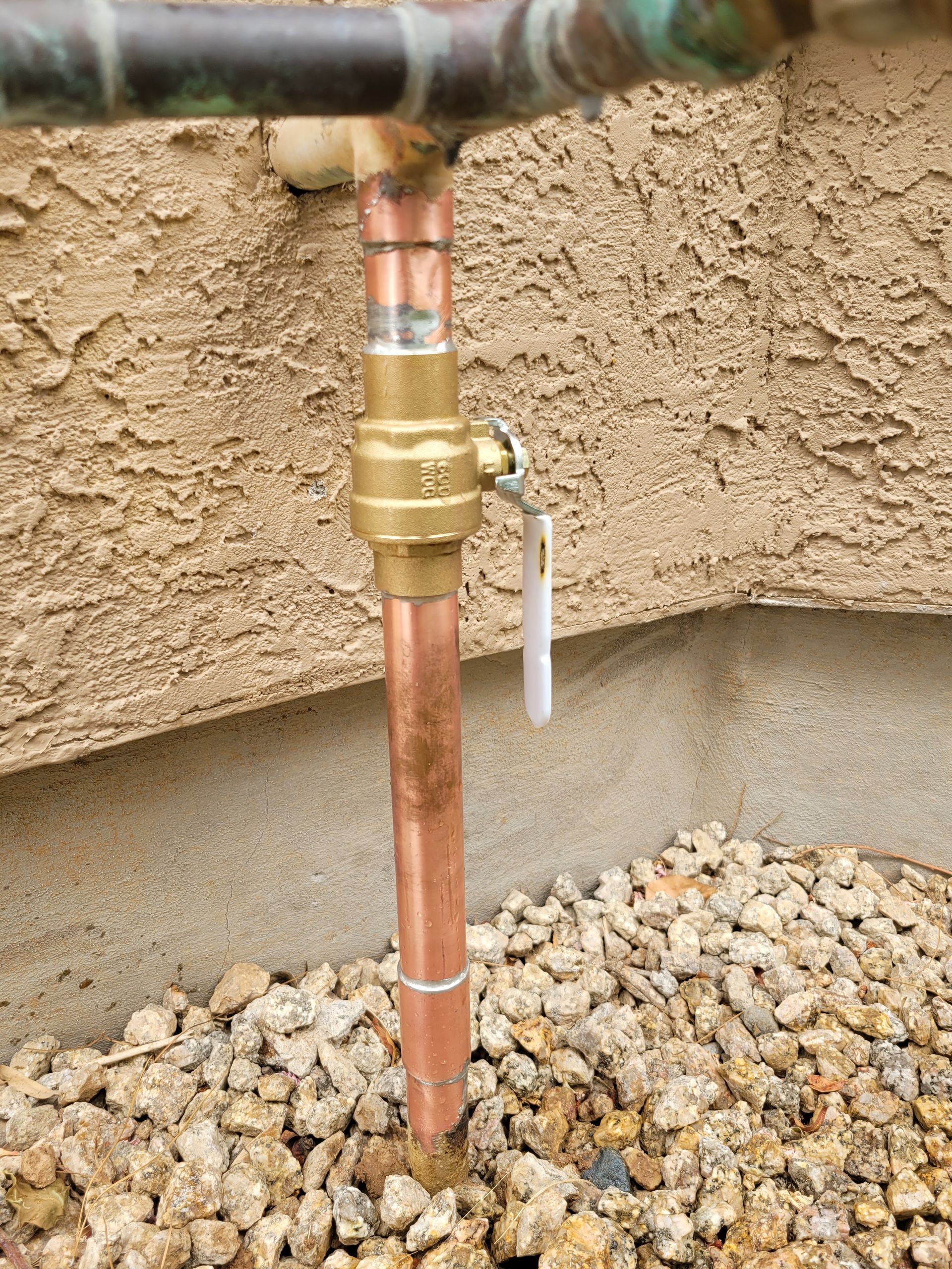 A close up of a copper pipe with a valve attached to it.