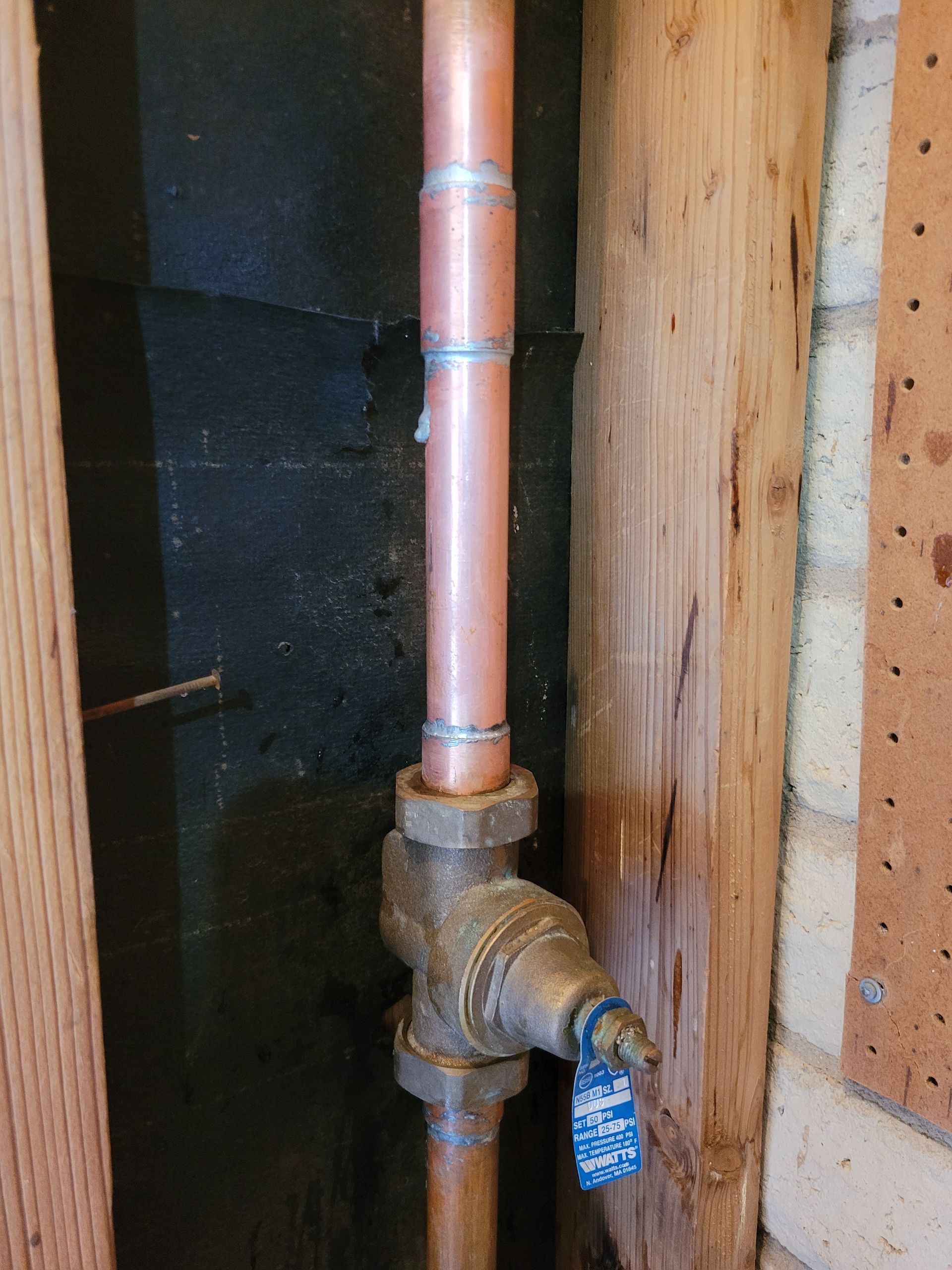 A close up of a copper pipe with a blue valve attached to it.