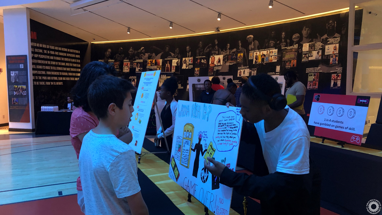 Young man describes his poster about gambling data to a woman and child