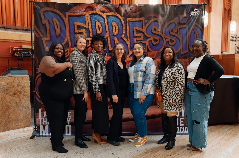 PHIWM staff and partners stand in front of banner that says