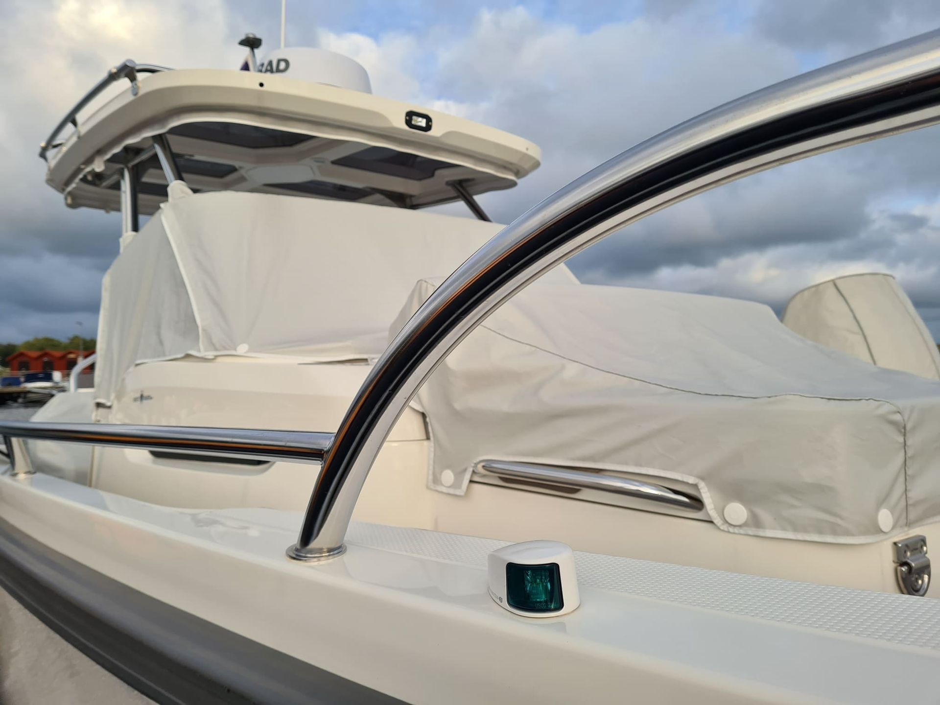 A white boat with a stainless steel railing and a light on the side.