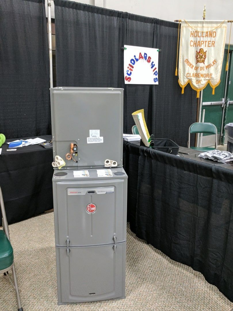 Gray water dispenser at an indoor booth with black drapes and a white sign in the background