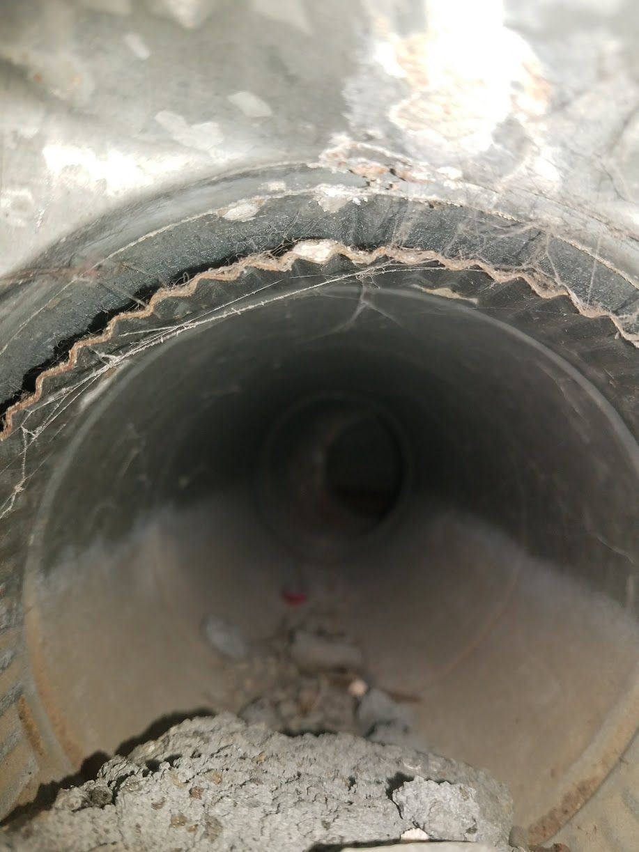 Interior of a large concrete pipe with cracked, crumbling edges and debris on the floor