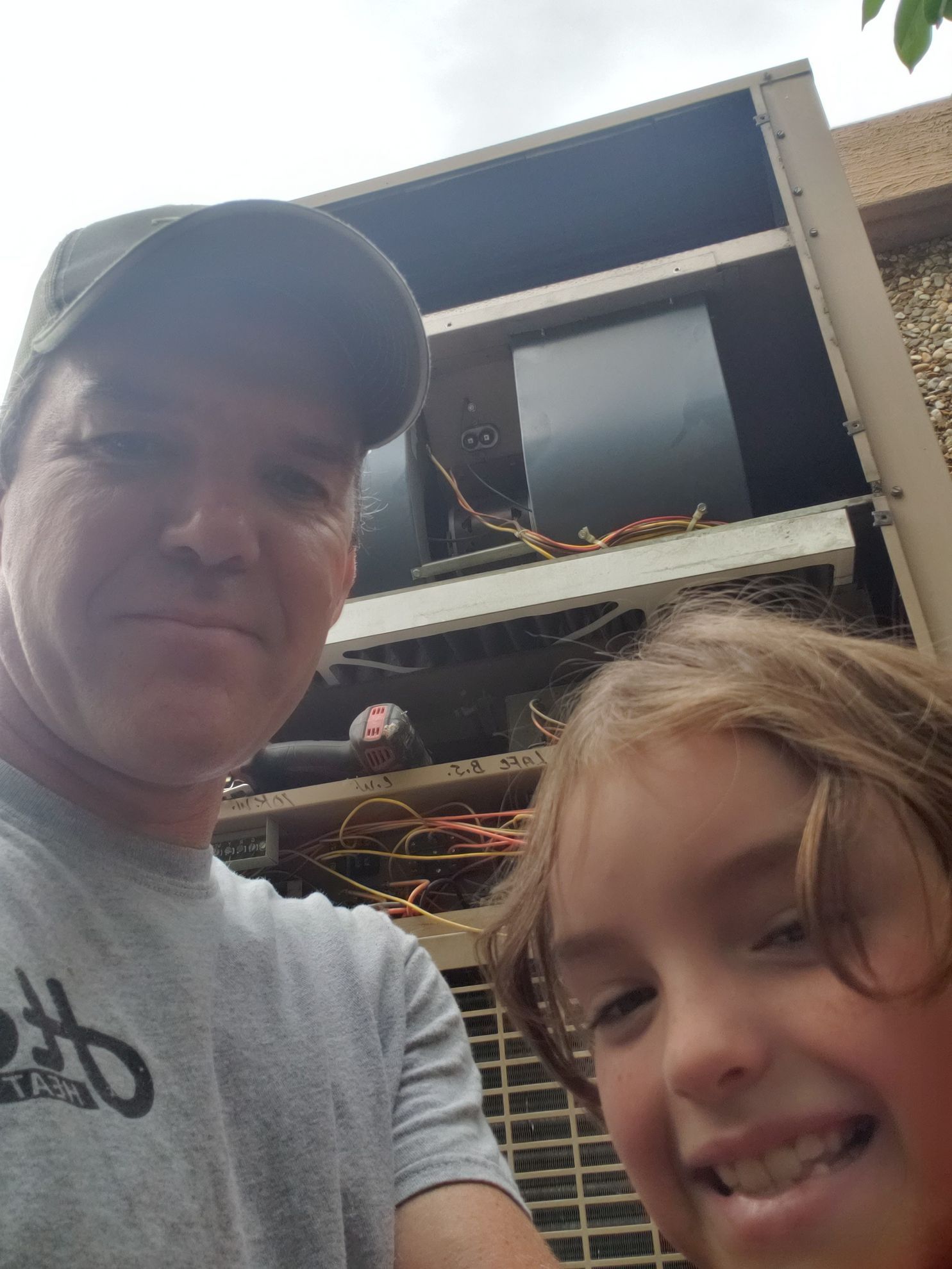 Selfie of two smiling people outdoors in front of a large truck or trailer.