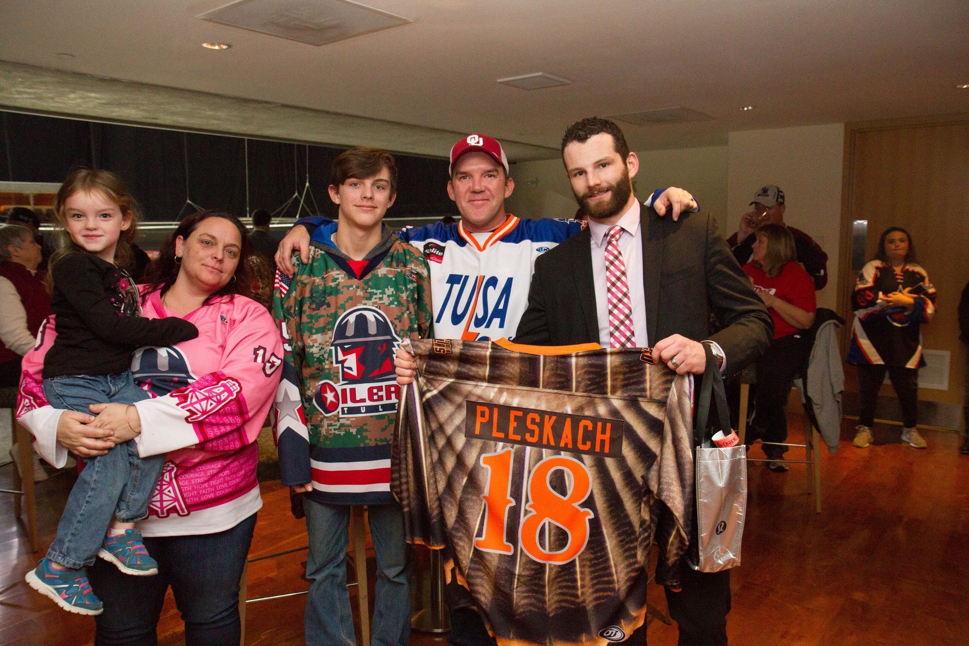 Group of fans posing indoors, one holding a child and one holding a jersey reading “Plesac 18”