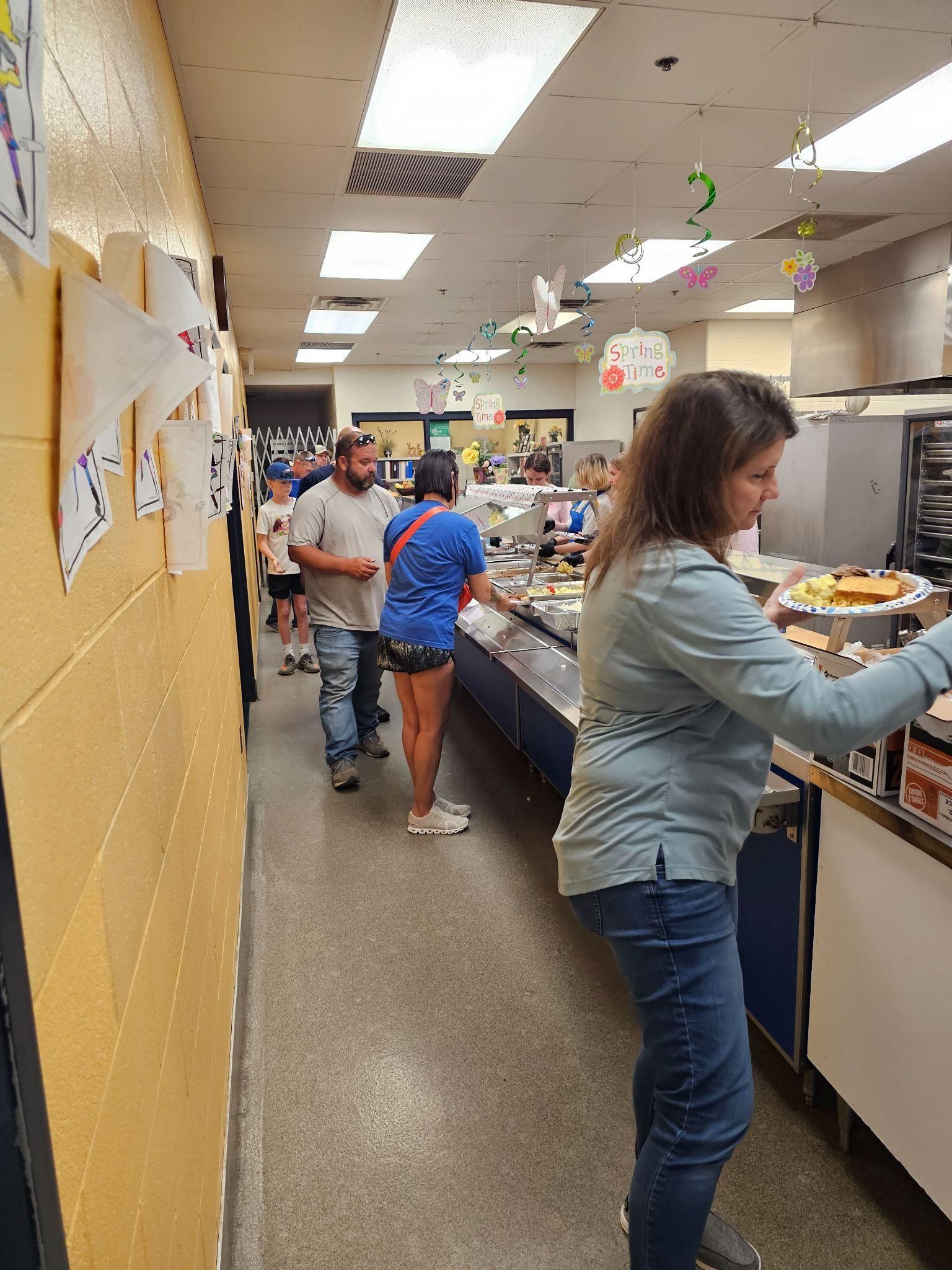 People sorting items along a long counter in a brightly lit mailroom or office workspace.
