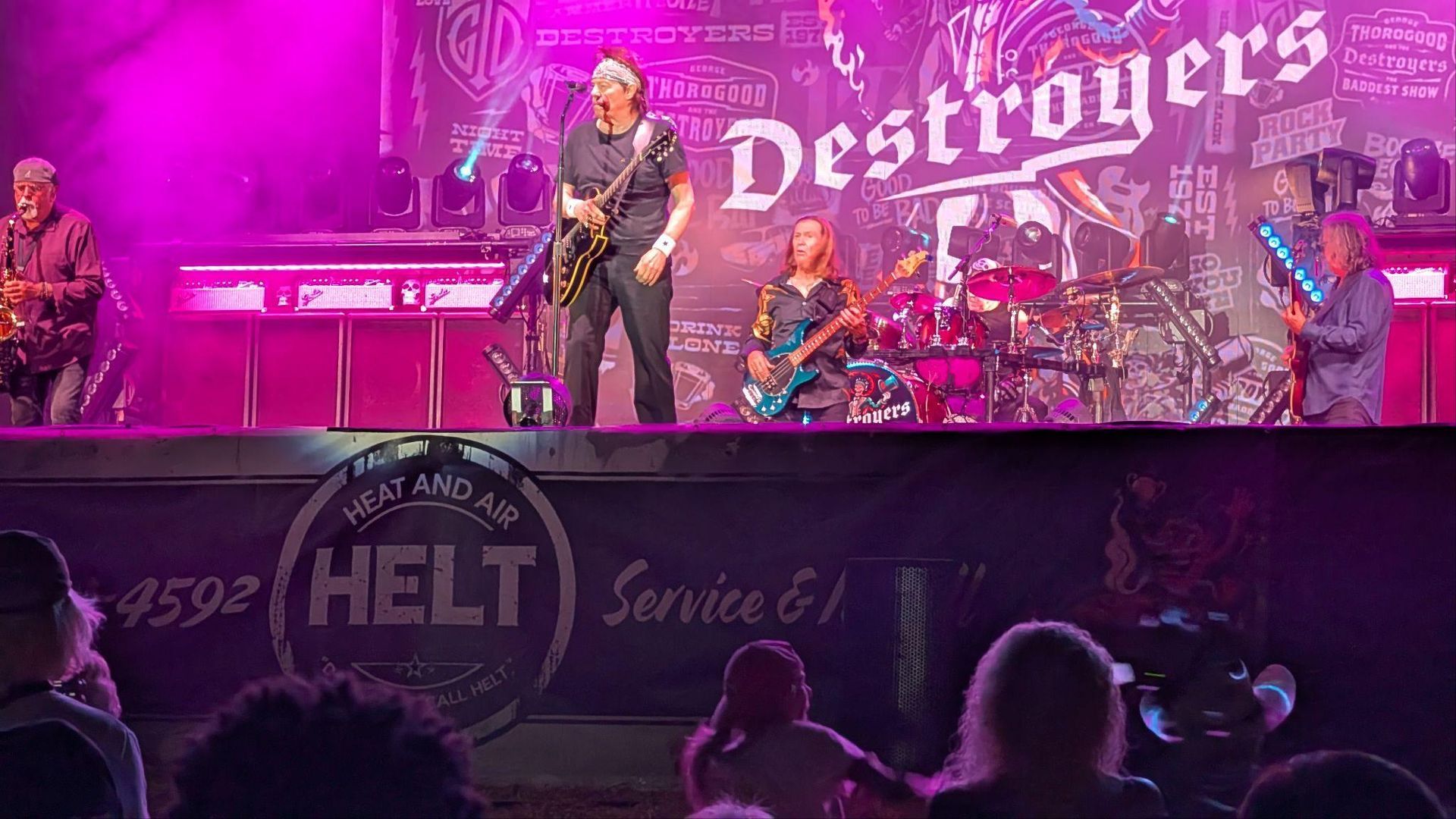Rock band performing on a pink-lit stage with “Destroyer’s” banner and audience silhouettes in front
