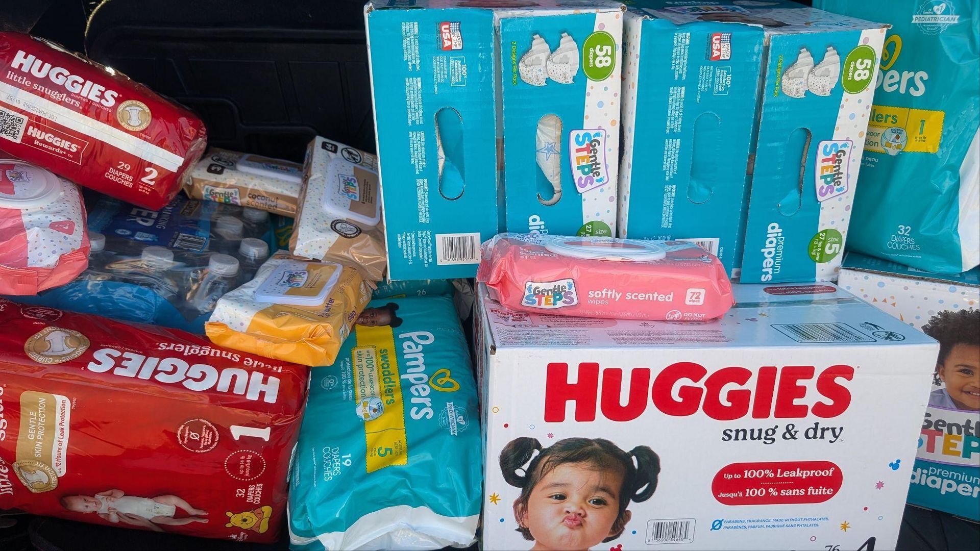 Stacks of Huggies diaper packages in blue, white, and red on store shelves