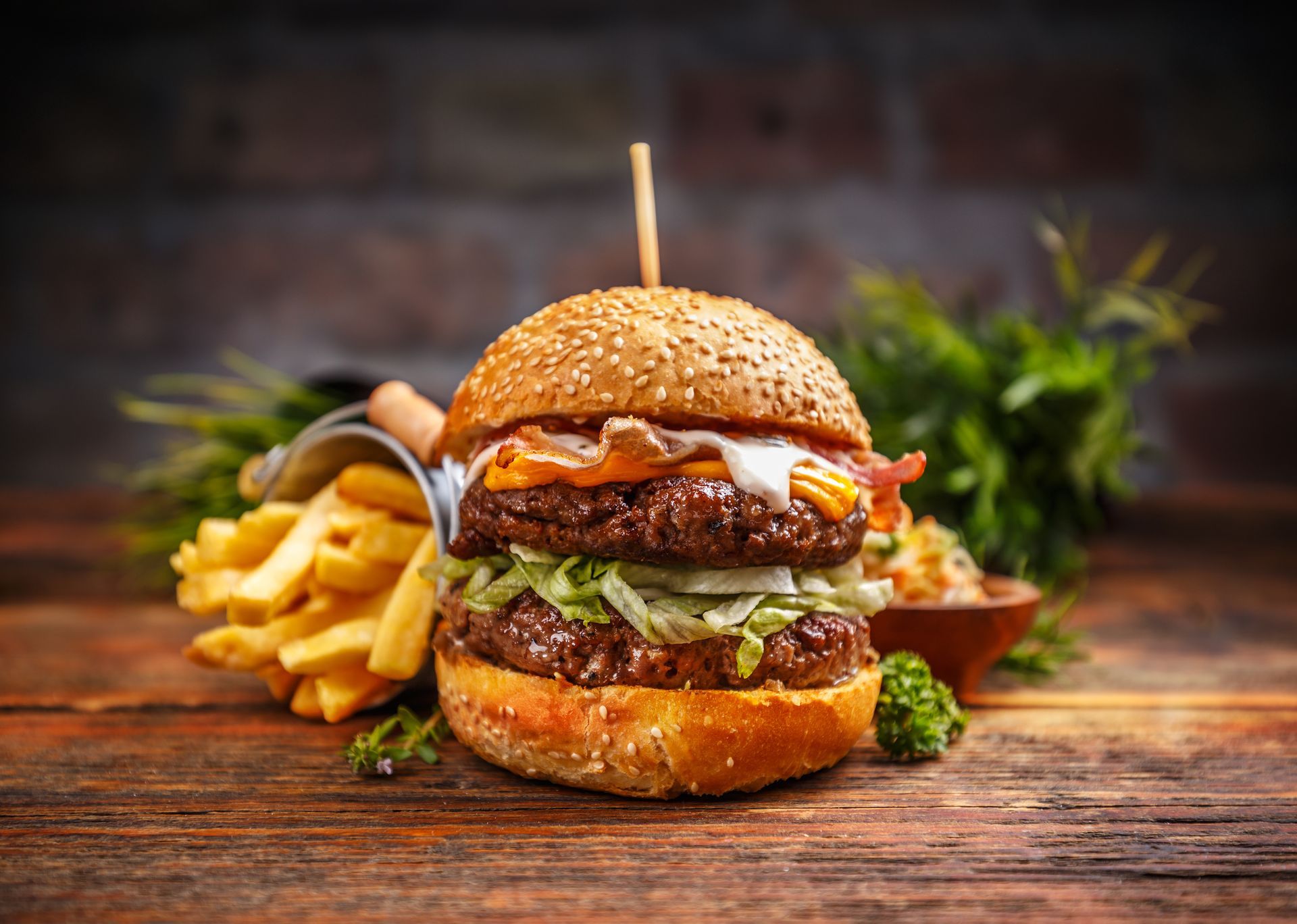 A double cheeseburger and french fries on a wooden table.
