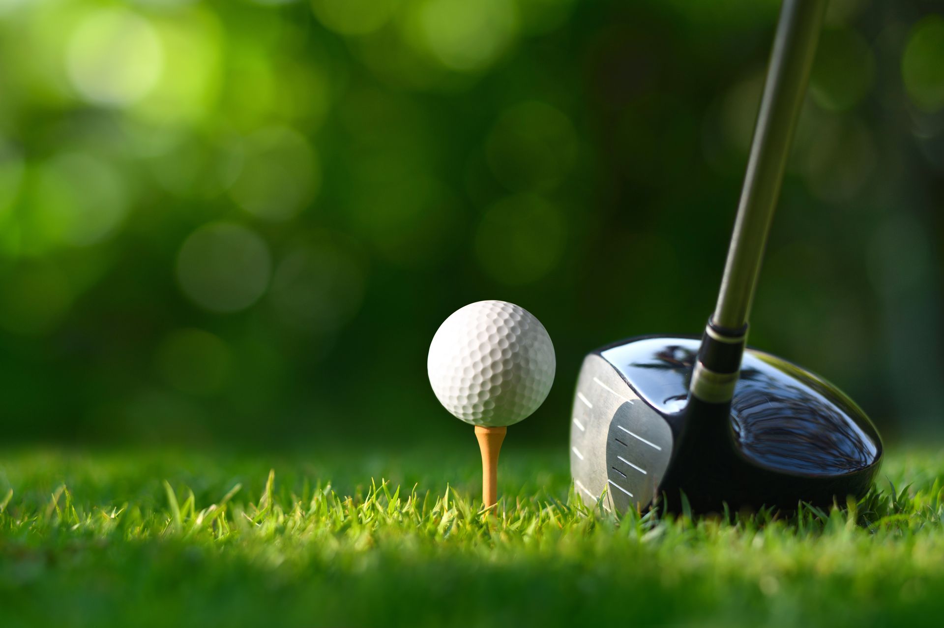 A golf ball is on a tee next to a golf club.