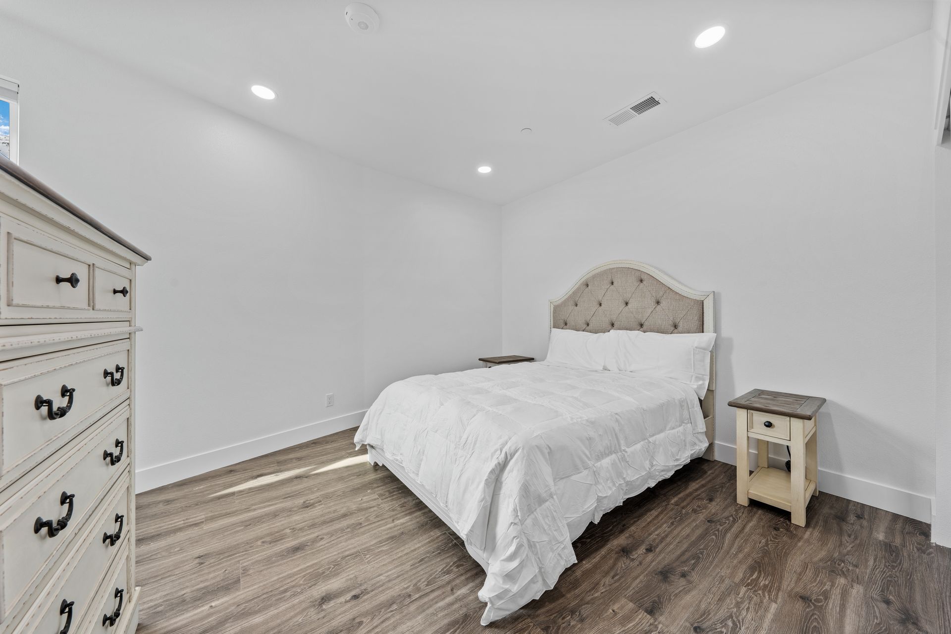 A bedroom with a bed , dresser and nightstand.